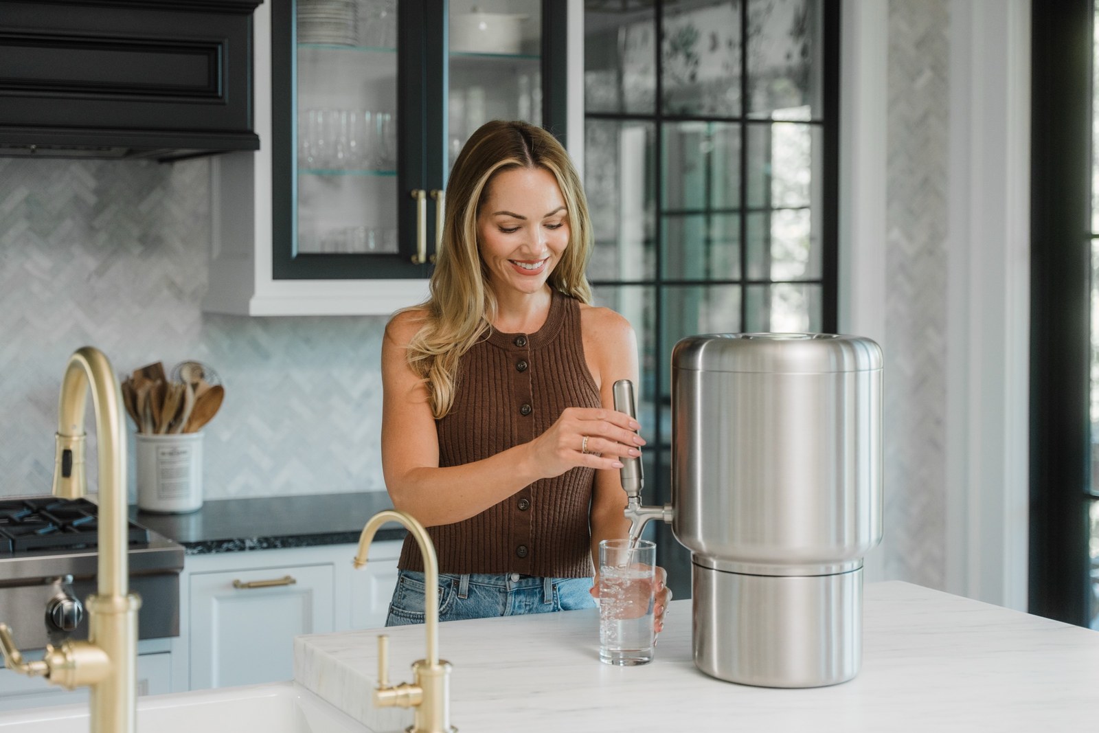 Woman filling a glass from the Rorra Countertop system in a modern kitchen