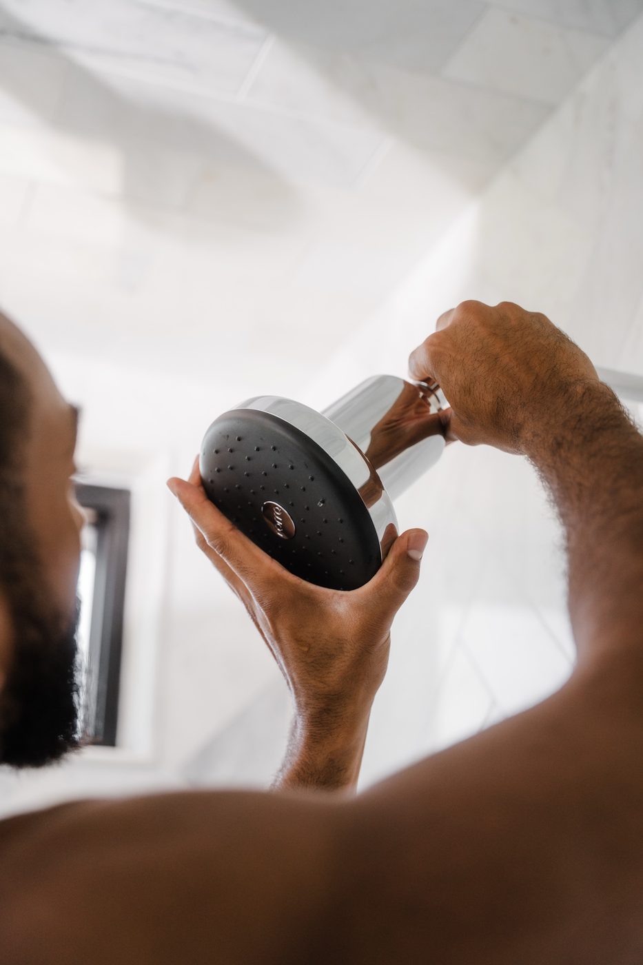 Man standing under a Rorra Showerhead in a bright shower