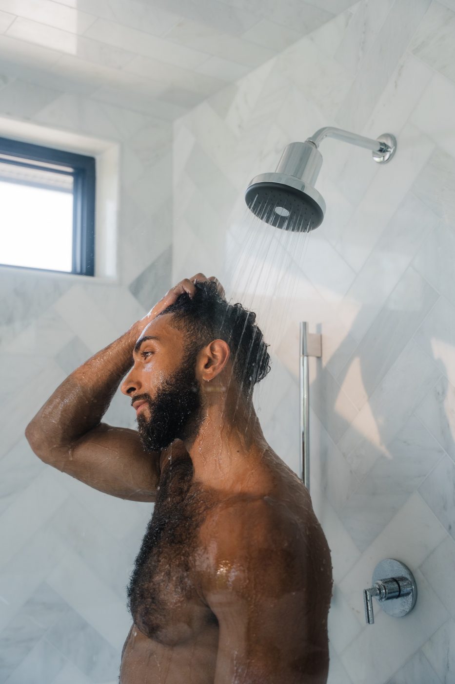 Hands adjusting a Rorra Showerhead on marble