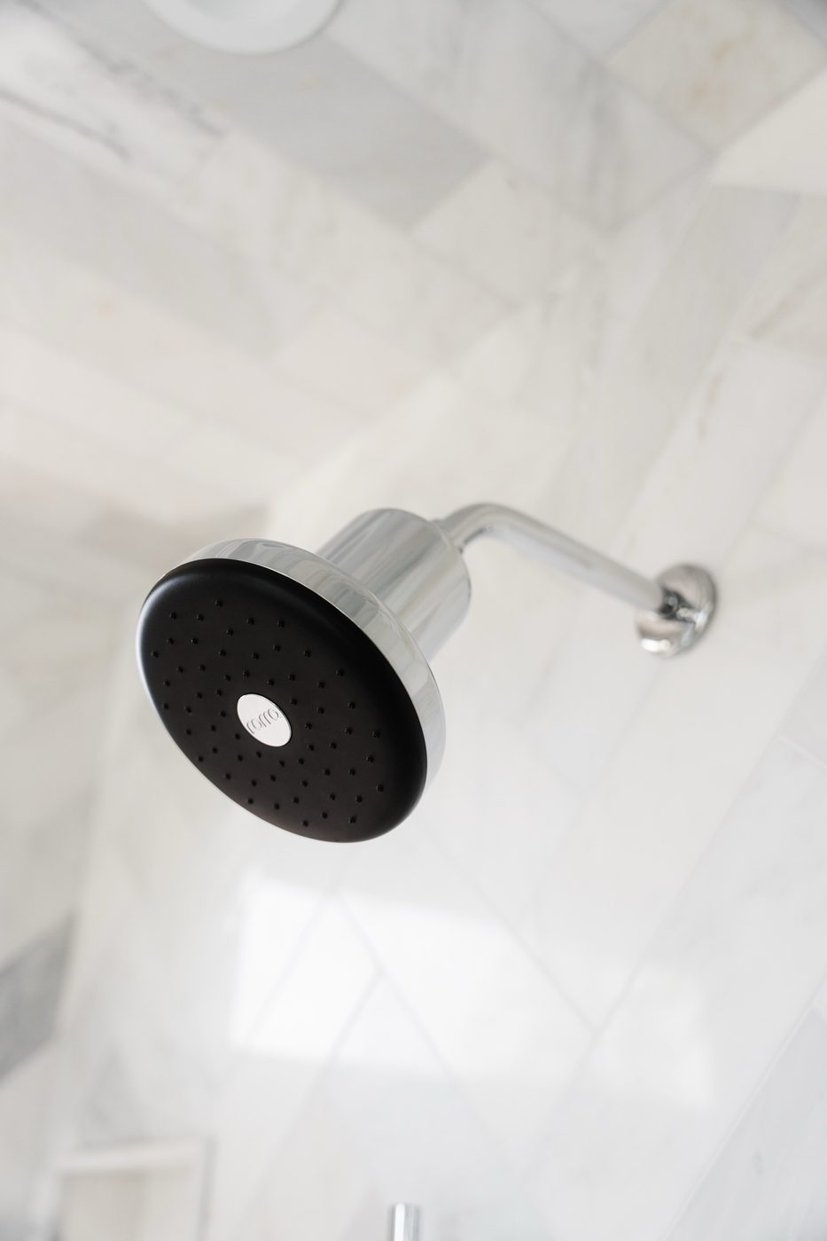 Low-angle view of a Rorra Showerhead on white tile